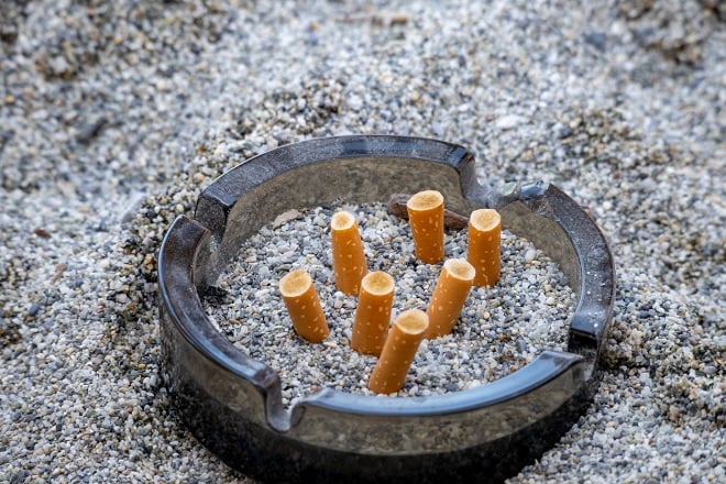 cendrier rempli de mégots de cigarettes et graviers trouvés sur une plage