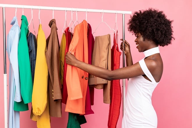 jeune femme joyeuse choisissant parmi des vêtements de couleur