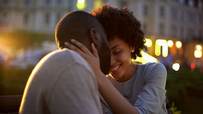 jeune couple se prenant les bras sur un banc dans la rue