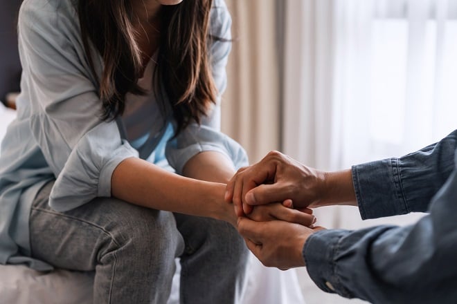 homme réconfortant sa femme en la prenant par les mains