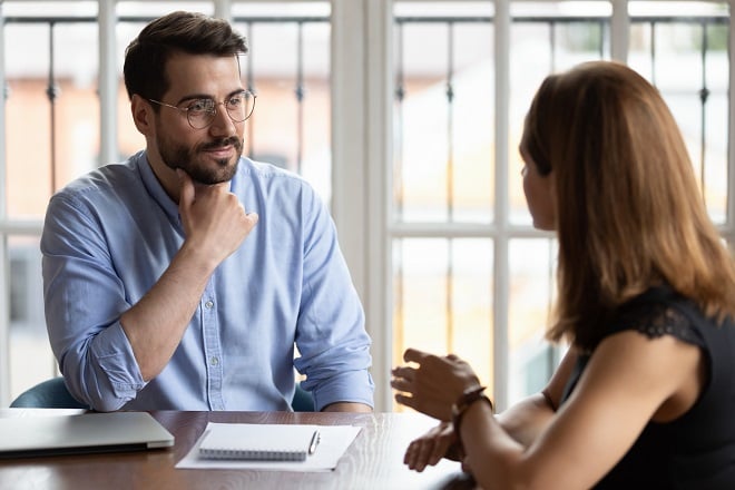 jeune homme écoutant son interlocutrice au travail