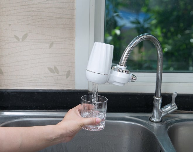 personne versant de l'eau dans un verre provenant d'un filtre à eau