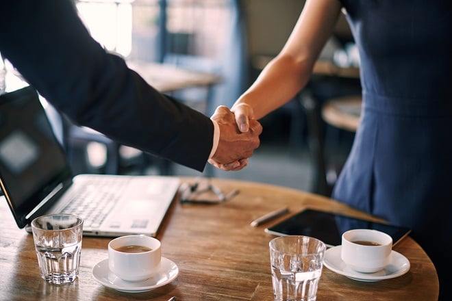 deux employés se serrant la main autour d'un café