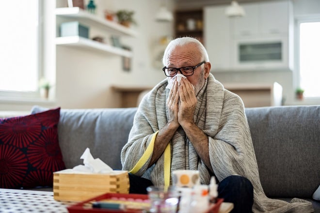 homme âgé grippé se mouchant 