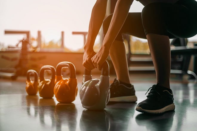 femme soulevant différents poids d'haltères dans une salle de sport