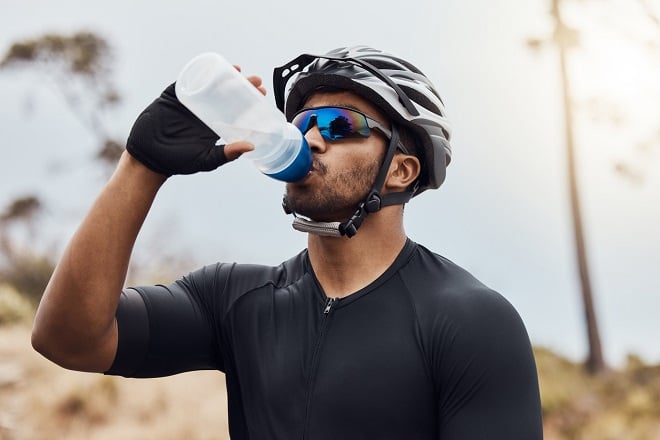 jeune homme sportif buvant de l'eau de sa gourde