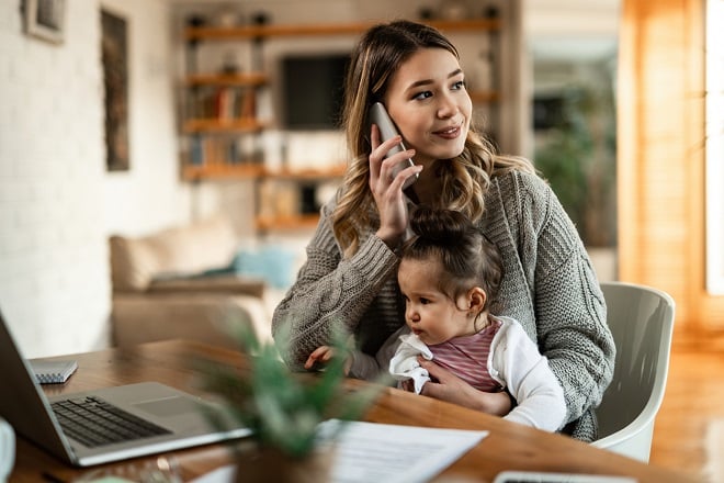 mère de famille avec son enfant dans les bras et au téléphone