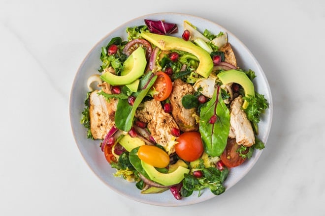 Assiette de salade de poulet à l'avocat et tomates cerises.