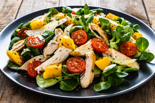 Assiette de poulet à l'ananas et tomates cerises avec des herbes aromatiques.