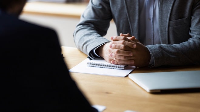 gros plan sur les mains croisées d'un employeur lors d'un entretien d'embauche