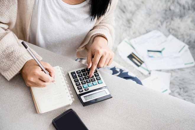 jeune femme tenant son budget dans un carnet avec une calculatrice