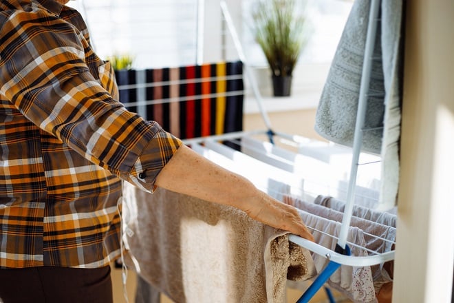 personne étendant du linge sur un étendoir à l'intérieur