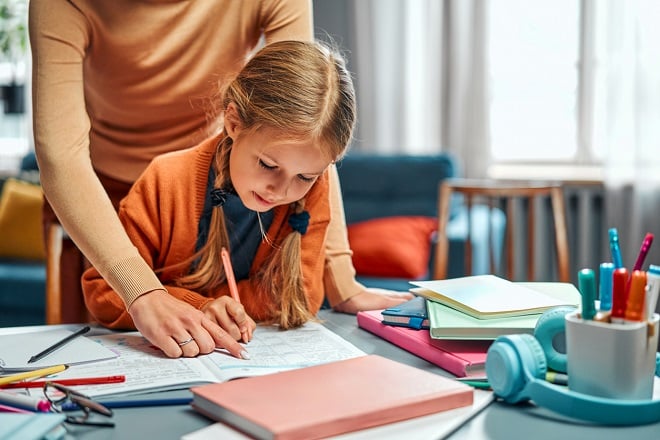 Professeure aidant une jeune élève à ses devoirs 