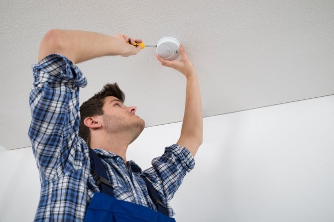 technicien installant un détecteur au plafond 