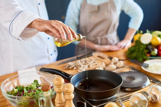 chef versant un filet d'huile dans une poêle