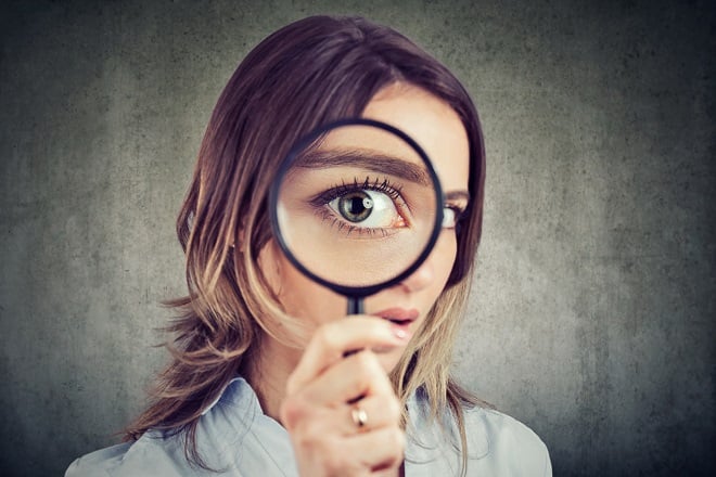 jeune femme regardant à travers une loupe et dévoilant la couleur de son oeil