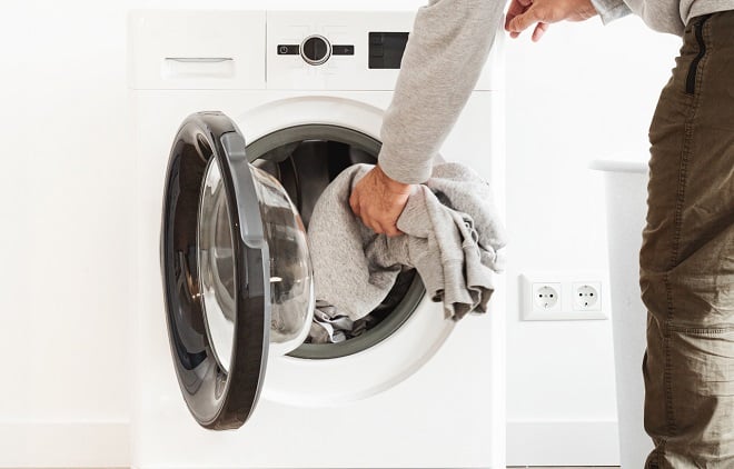 un homme mettant du linge dans la machine à laver