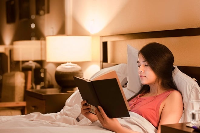 jeune femme lisant un livre dans son lit