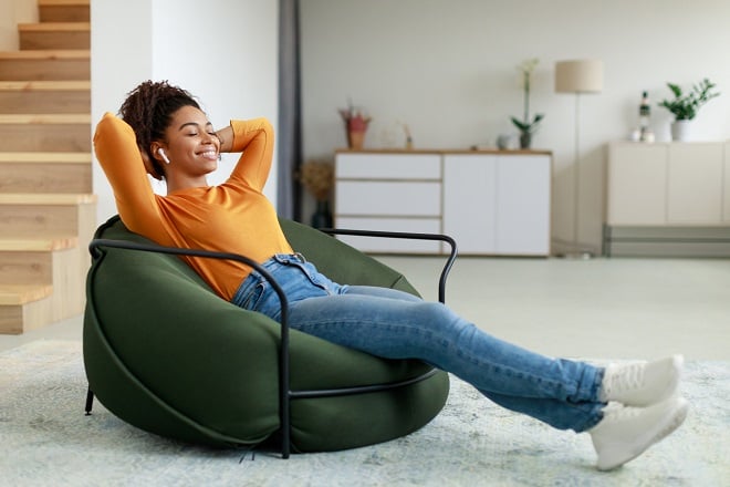 Jeune femme heureuse et écoutant de la musique sur un fauteuil 