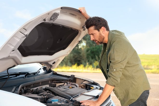 Homme regardant le moteur de sa voiture