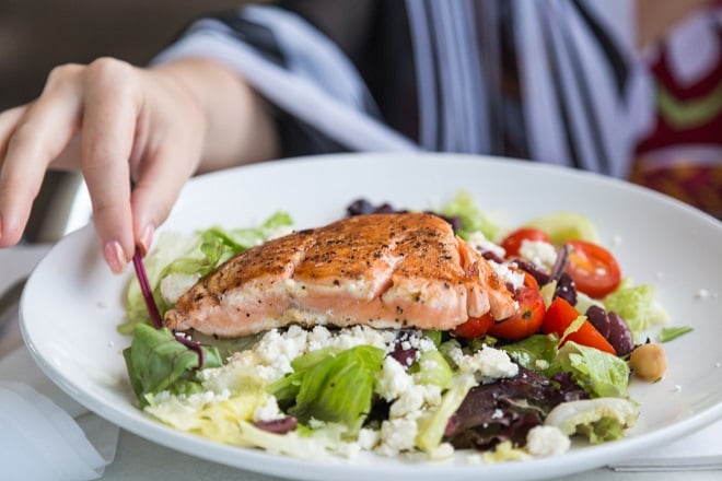 Personne mangeant un plat équilibré contenant du poisson