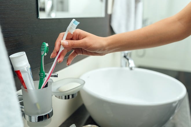 femme remettant sa brosse à dents dans le porte-brosses à dents