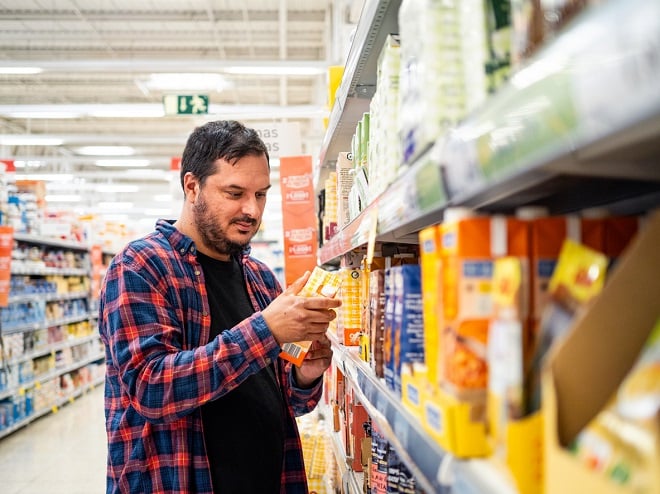 Homme regardant l'étiquette d'un produit dans un rayon