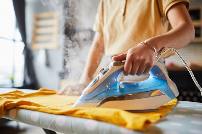 jeune femme en train de repasser un linge