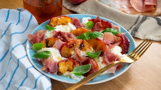 assiette de salade avec des pêches rôties de la burrata et du jambon