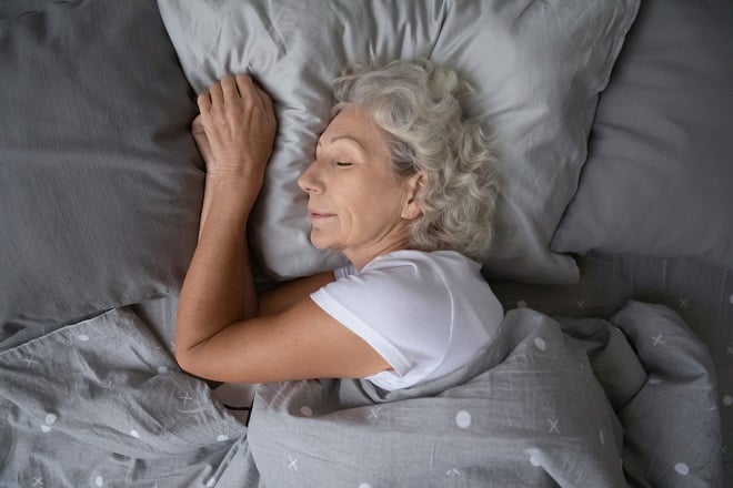 Femme âgée dormant sur le côté dans son lit