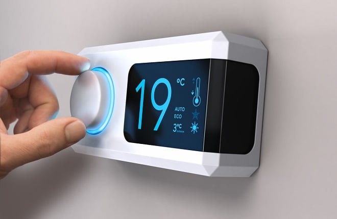 personne réglant un thermostat électrique